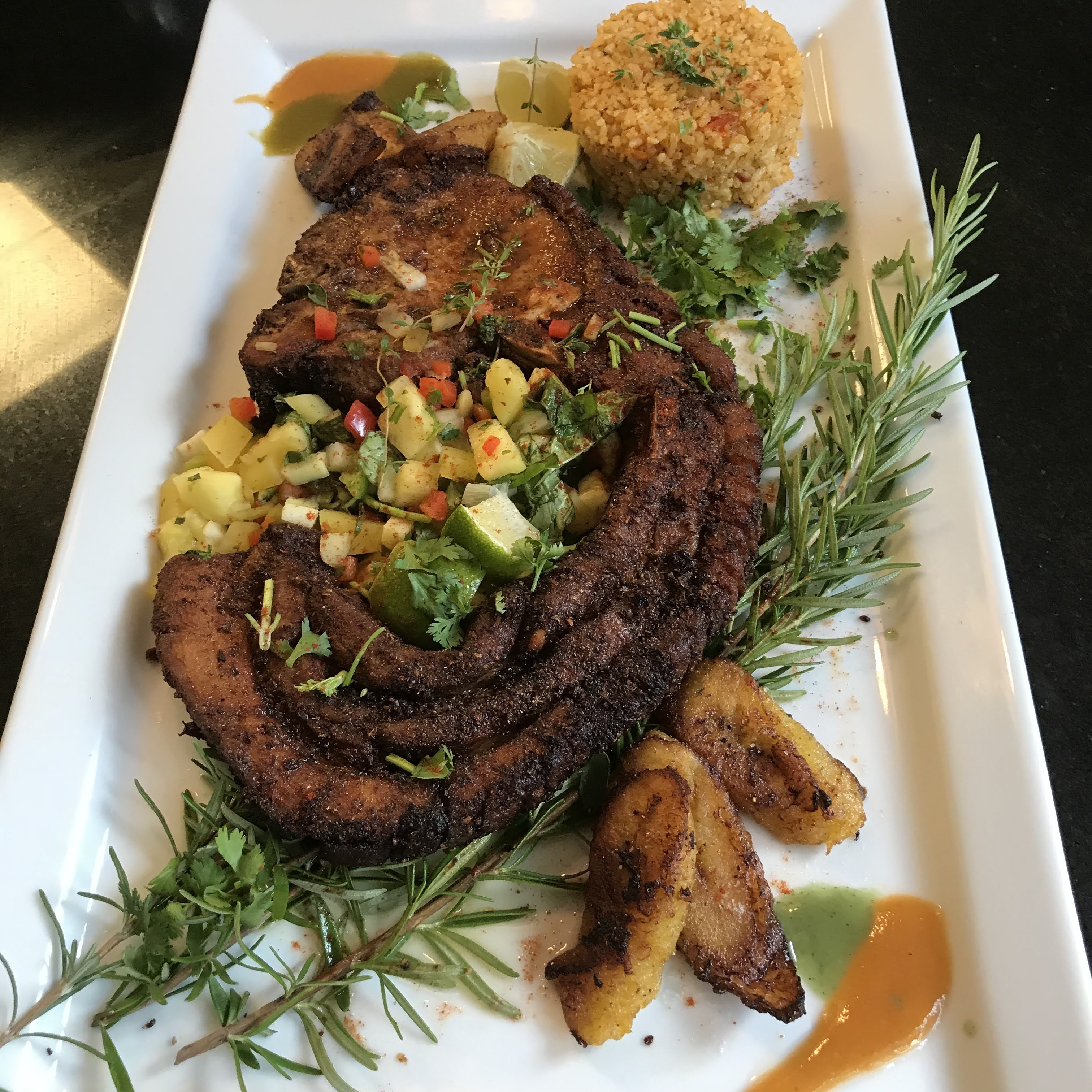 The finished plate — chuletas can-can with yellow rice, plantains, and salsa
